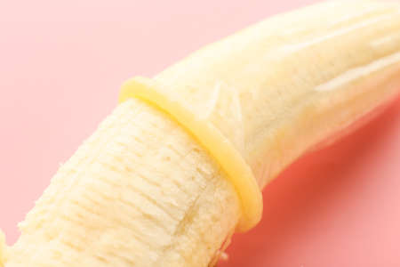 Banana with condom on color background, closeup. Erotic conceptの写真素材