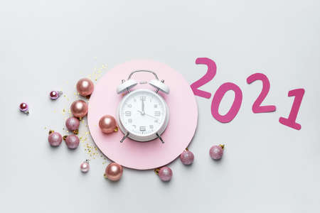 New Year composition with alarm clock and figure 2021 on light background