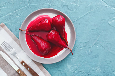 Plate of tasty poached pears in wine sauce on color backgroundの写真素材