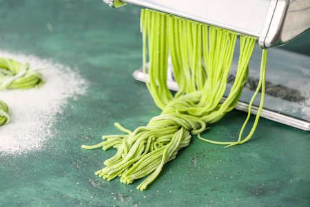 Pasta machine with dough on color backgroundの写真素材