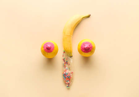 Painted lemons and banana with condom on color background. Erotic concept
