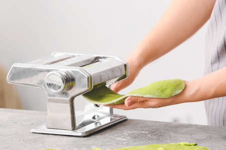 Woman with dough and pasta machine at table