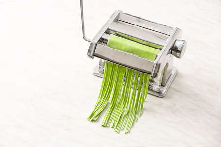 Pasta machine with dough on light background