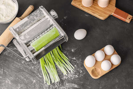 Pasta machine with dough on dark background