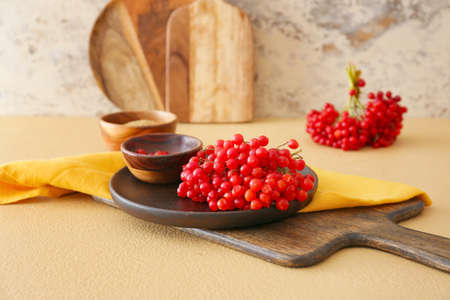 Plate with fresh viburnum berries on table