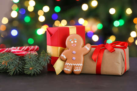 Christmas composition with gingerbread cookie and gifts on dark background with blurred lights