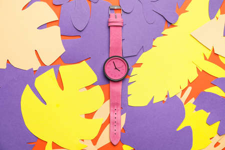 Wrist watch with paper tropical leaves on color backgroundの写真素材