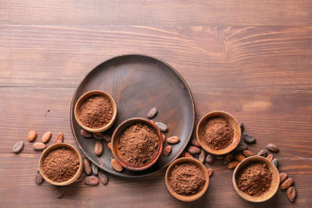Bowls with cacao powder and beans on wooden backgroundの写真素材