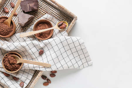 Tray with cacao powder, beans and chocolate on white backgroundの写真素材