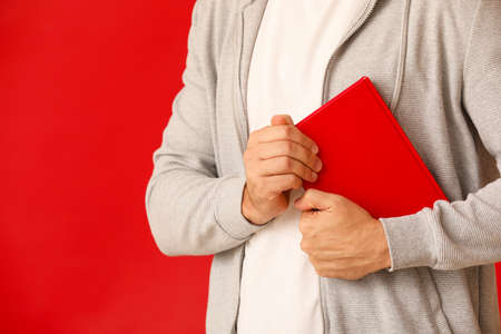 Man with book on color background, closeup