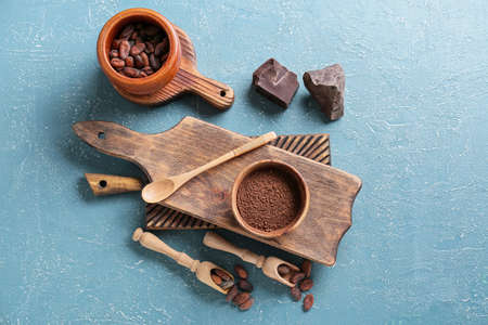 Cacao powder with beans and chocolate on color backgroundの写真素材