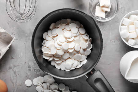 Saucepan with chocolate drops on gray backgroundの写真素材