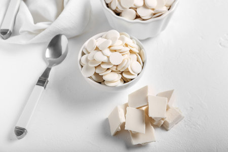 Bowl with chocolate drops on light background