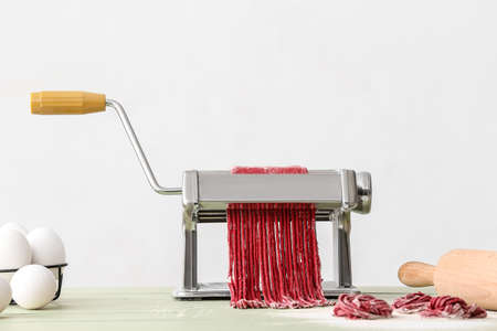 Pasta maker with dough on kitchen tableの写真素材