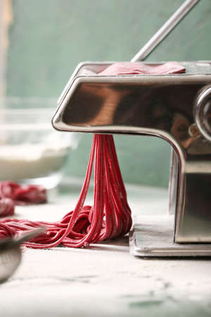 Pasta maker with dough on kitchen tableの写真素材