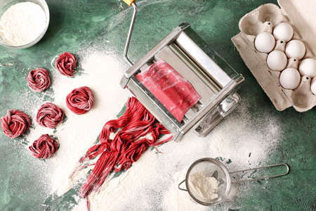Pasta maker with dough on color backgroundの写真素材