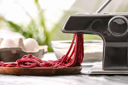 Pasta maker with dough on kitchen tableの写真素材