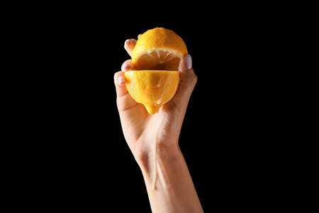 Hand with cut juicy lemon on dark background. Erotic conceptの写真素材