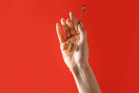 Hand with honey dipper on color background. Erotic conceptの写真素材