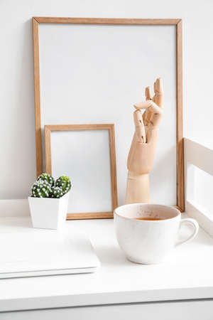 Wooden hand with laptop and cup of tea on table in interior of room