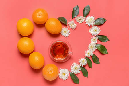 Composition with cup of tea, oranges and flowers on color backgroundの写真素材