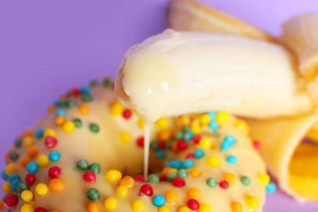 Banana and donut on color background, closeup. Erotic concept