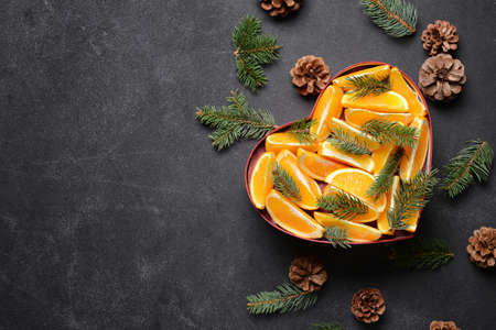 Heart made of oranges, pine cones and fir branches on dark backgroundの写真素材