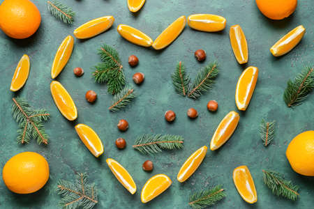 Heart made of cut oranges, fir branches and hazelnuts on color backgroundの写真素材