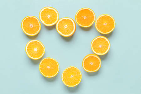 Heart made of cut oranges on color background