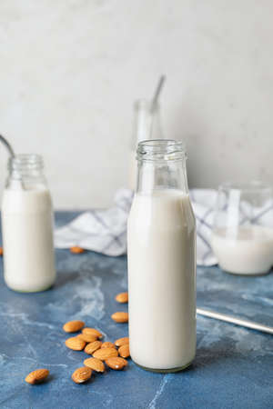 Bottles of tasty almond milk on color tableの写真素材