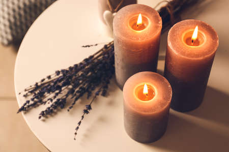 Beautiful aroma candles with lavender flowers on table
