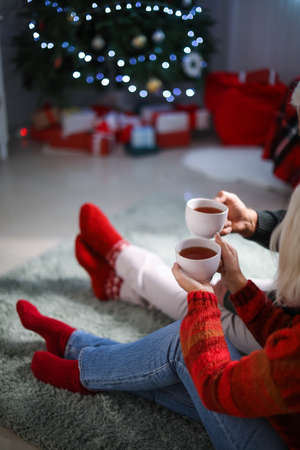 Mature couple with hot tea celebrating Christmas at homeの写真素材