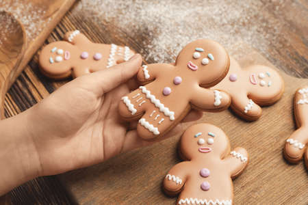 Woman holding Christmas gingerbread cookies on wooden background