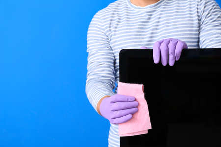 Young man cleaning computer on color backgroundの写真素材