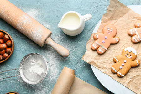 Gingerbread cookies and ingredients on color background