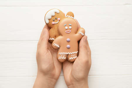 Woman holding Christmas gingerbread cookies on wooden backgroundの写真素材