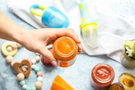 Woman holding jar with healthy baby food on color background, closeupの写真素材