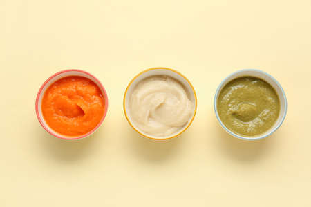 Bowls with healthy baby food on color backgroundの写真素材