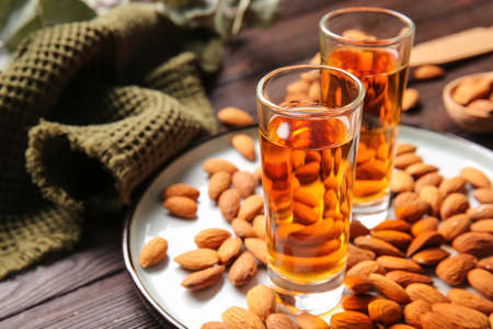 Tray with glasses of almond liquor and nuts on wooden background, closeupの写真素材
