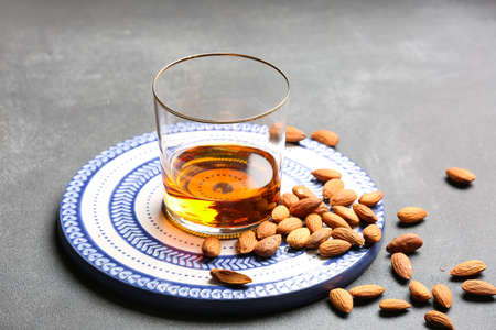 Glass of almond liquor and nuts on dark background