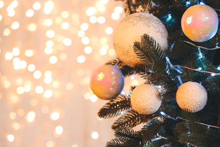 Christmas balls hanging on fir tree against blurred lightsの写真素材