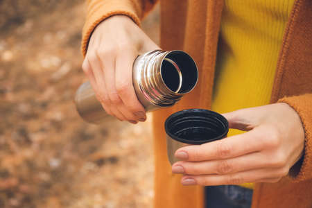 Young woman with drinking hot tea in forest, closeup