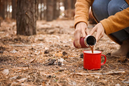 Young woman with drinking hot tea in forestの写真素材