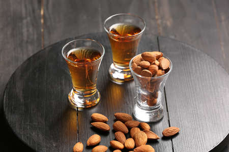 Tray with glasses of almond liquor and nuts on dark wooden background