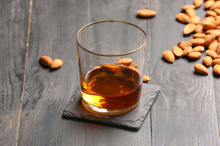 Glass of almond liquor and nuts on dark wooden backgroundの写真素材