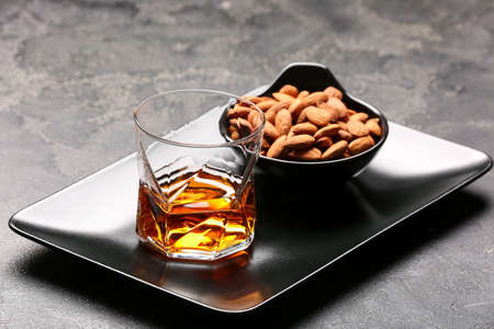 Tray with glass of almond liquor and nuts on dark backgroundの写真素材