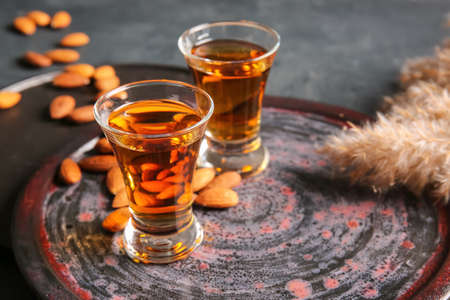 Tray with glasses of almond liquor and nuts on dark background, closeupの写真素材