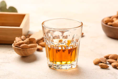 Glass of almond liquor and nuts on light background, closeupの写真素材