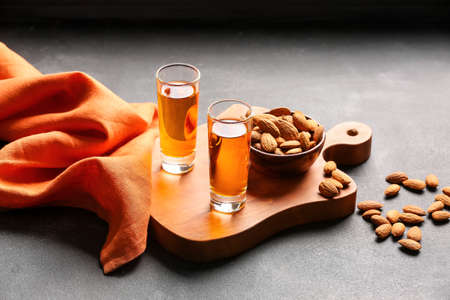 Board with glasses of almond liquor and nuts on dark backgroundの写真素材