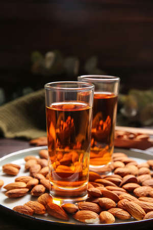Tray with glasses of almond liquor and nuts on dark background, closeupの写真素材